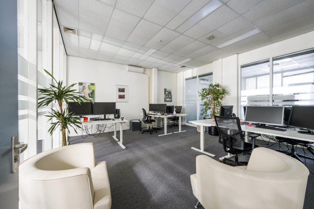 Modern office space at Van der Madeweg with multiple workstations, ergonomic chairs, indoor plants, and natural light.